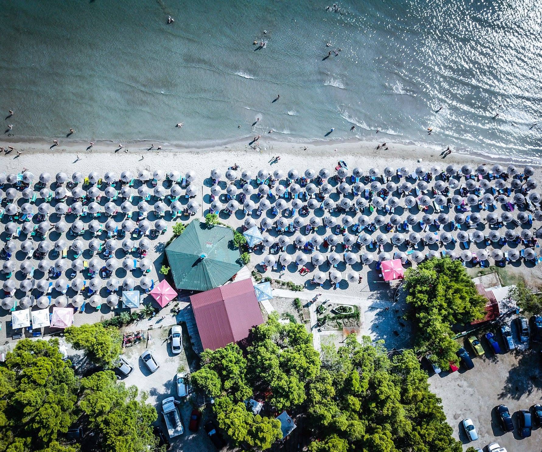 Aerial view of Algedi beach with rows of parasols and sunbeds in Zvernec, Vlore